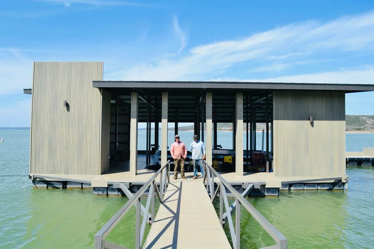 Two people standing at the end of the gangway in front of the finished boathouse