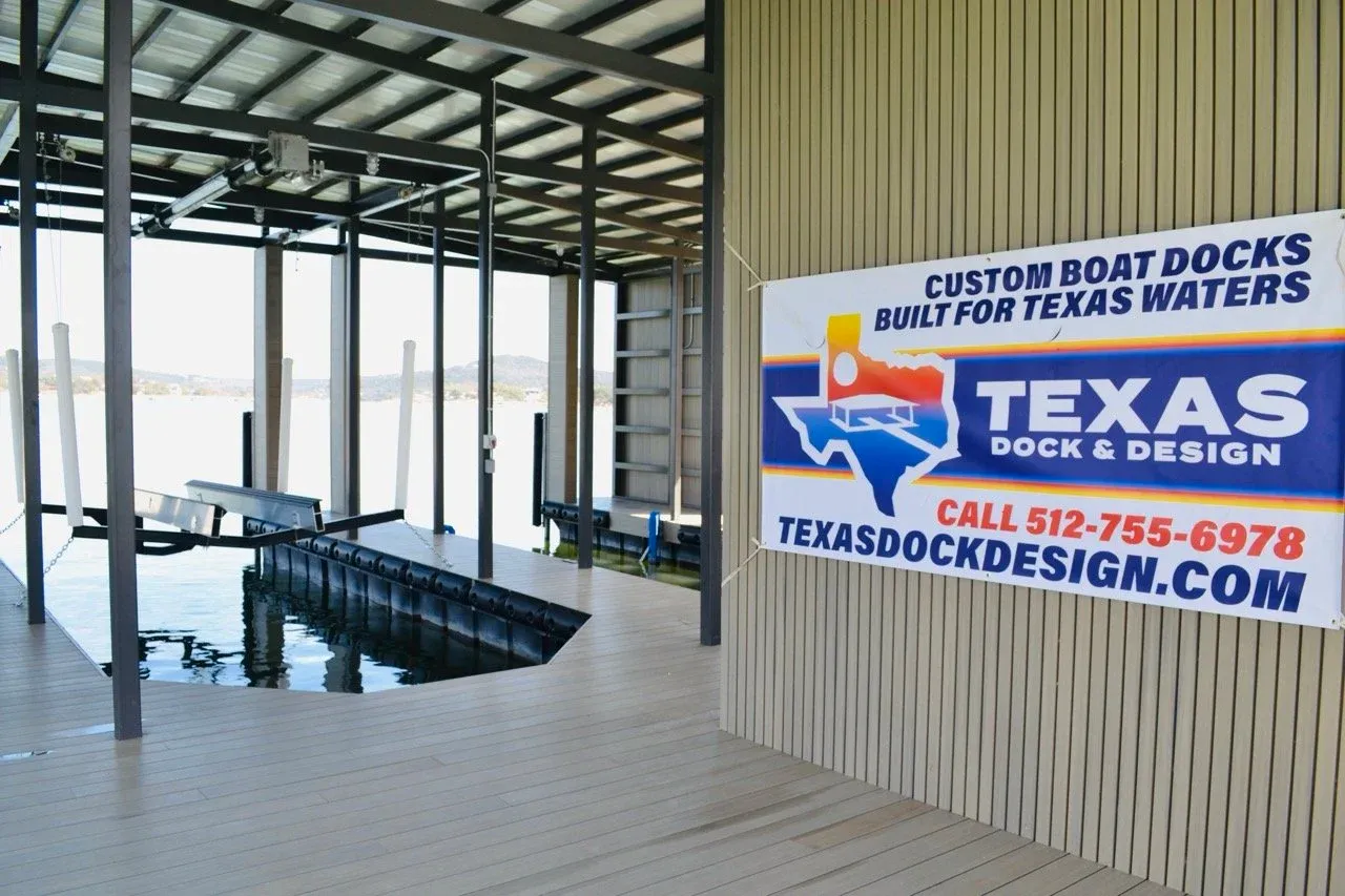 Empty boat slip inside the boathouse with a Texas Dock and Design banner on the wall