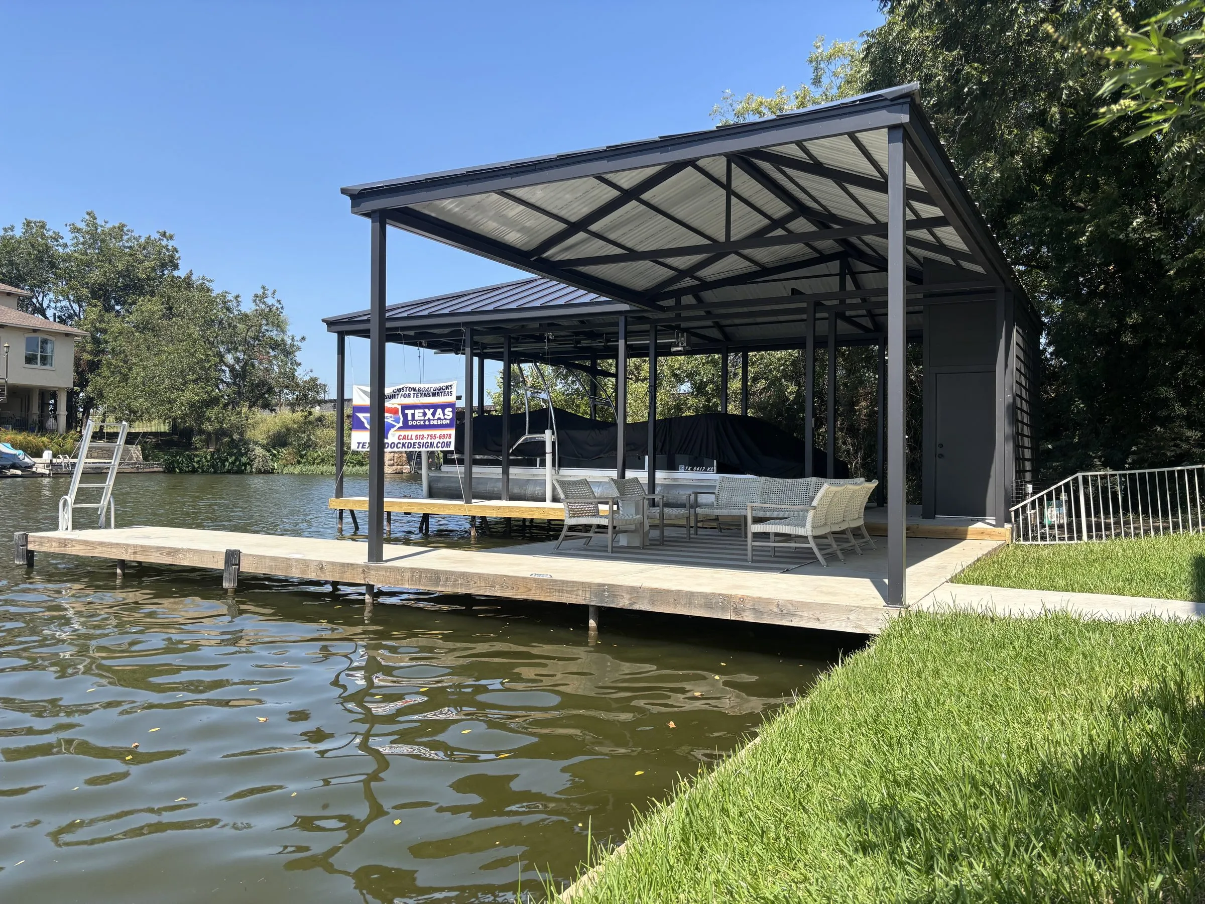 Covered stationary dock with patio seating and a Texas Dock & Design banner