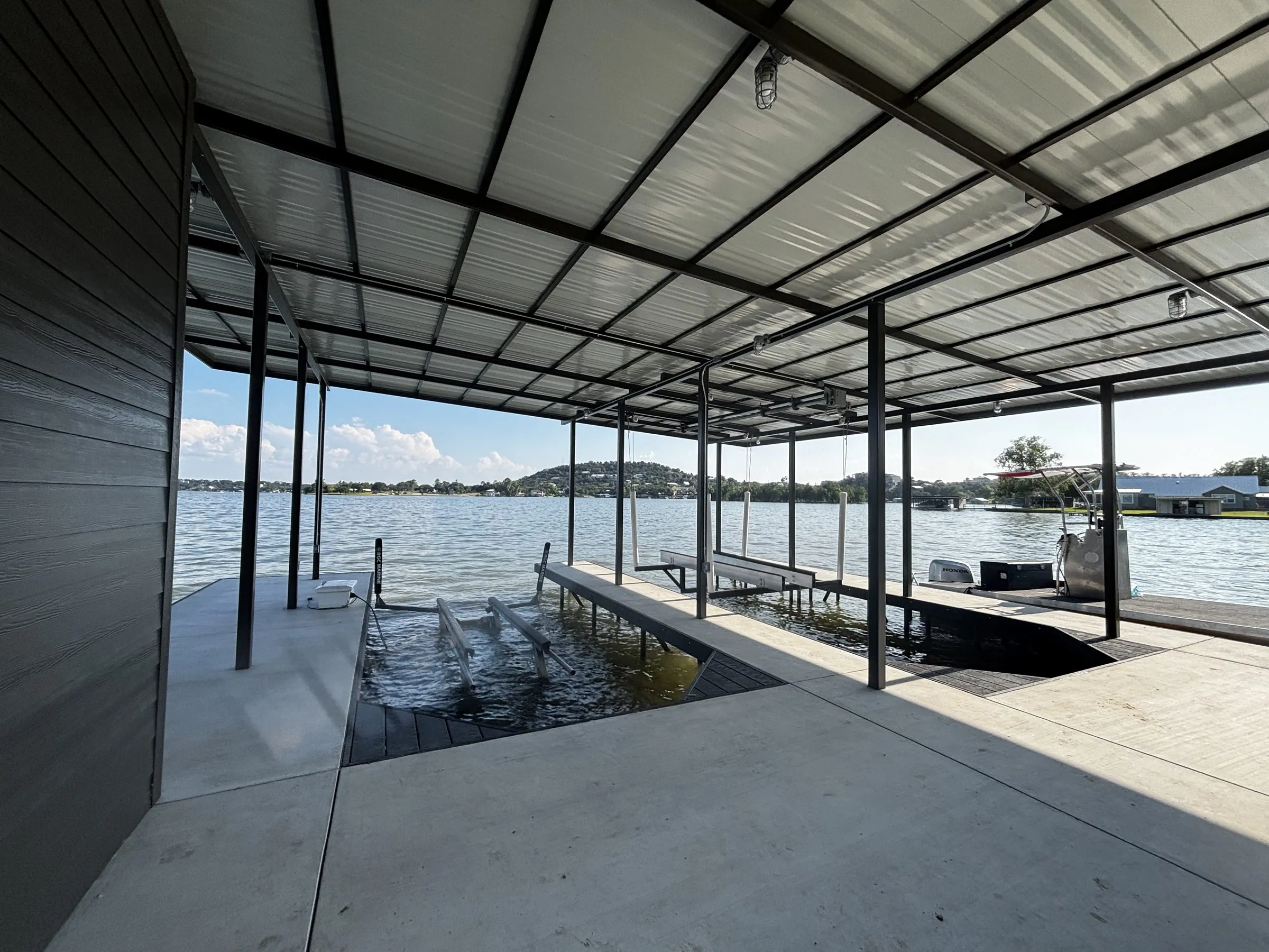 Concrete walkway along the slips under the boathouse roof, with the lake beyond