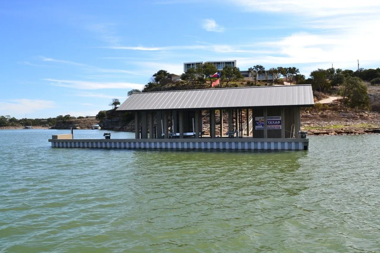 Wide view of the floating boathouse with the hillside and lake house behind it