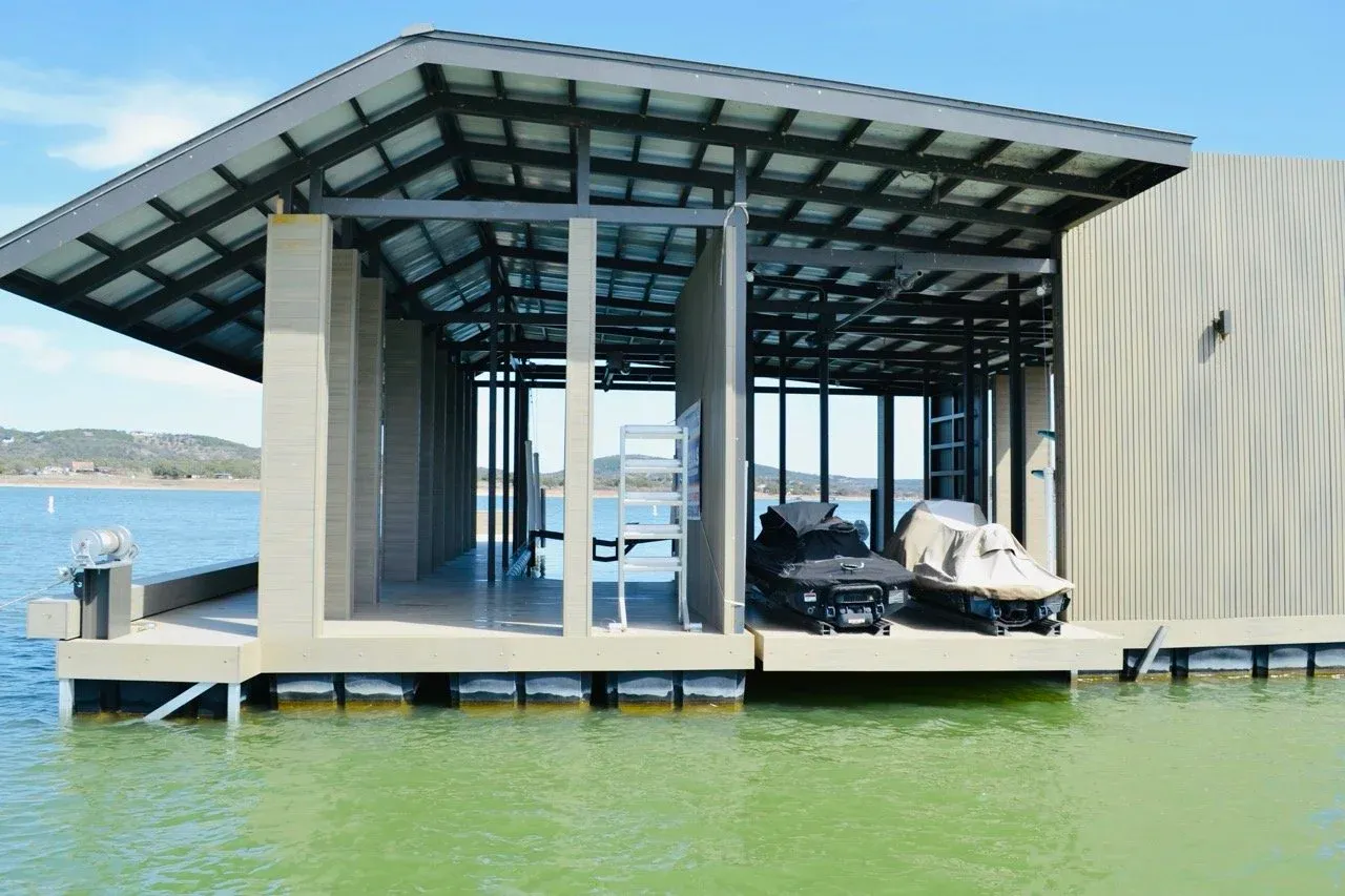 Interior of the boathouse with jet skis on lifts under the steel roof framing