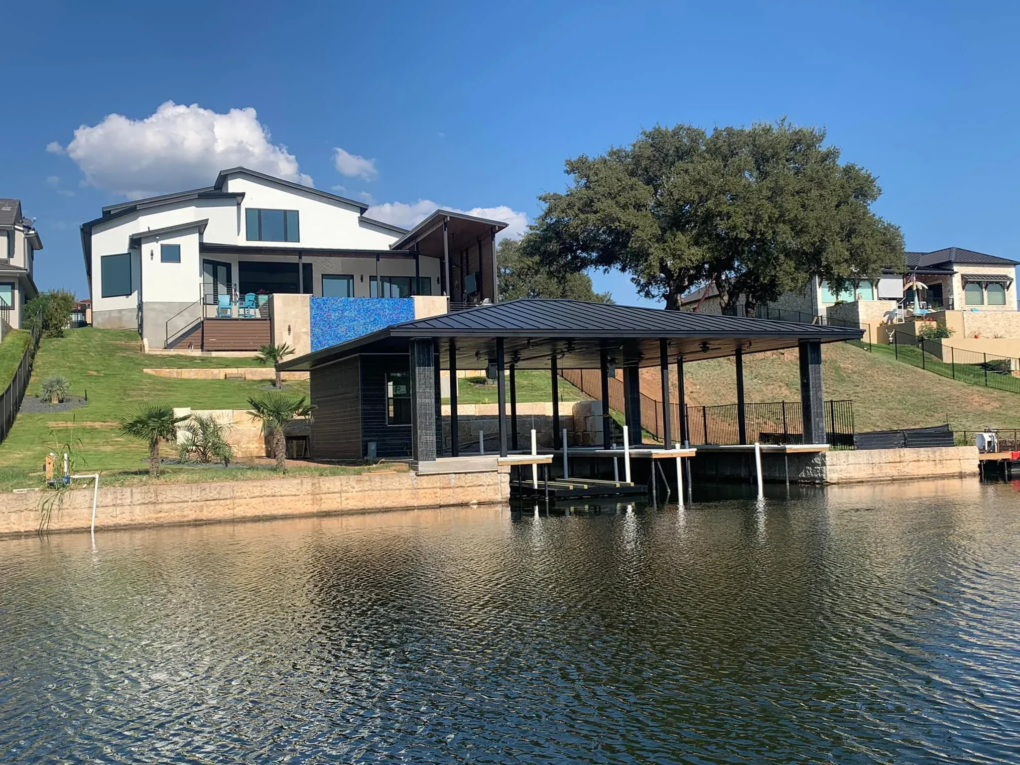 Covered stationary dock in front of a modern lake house