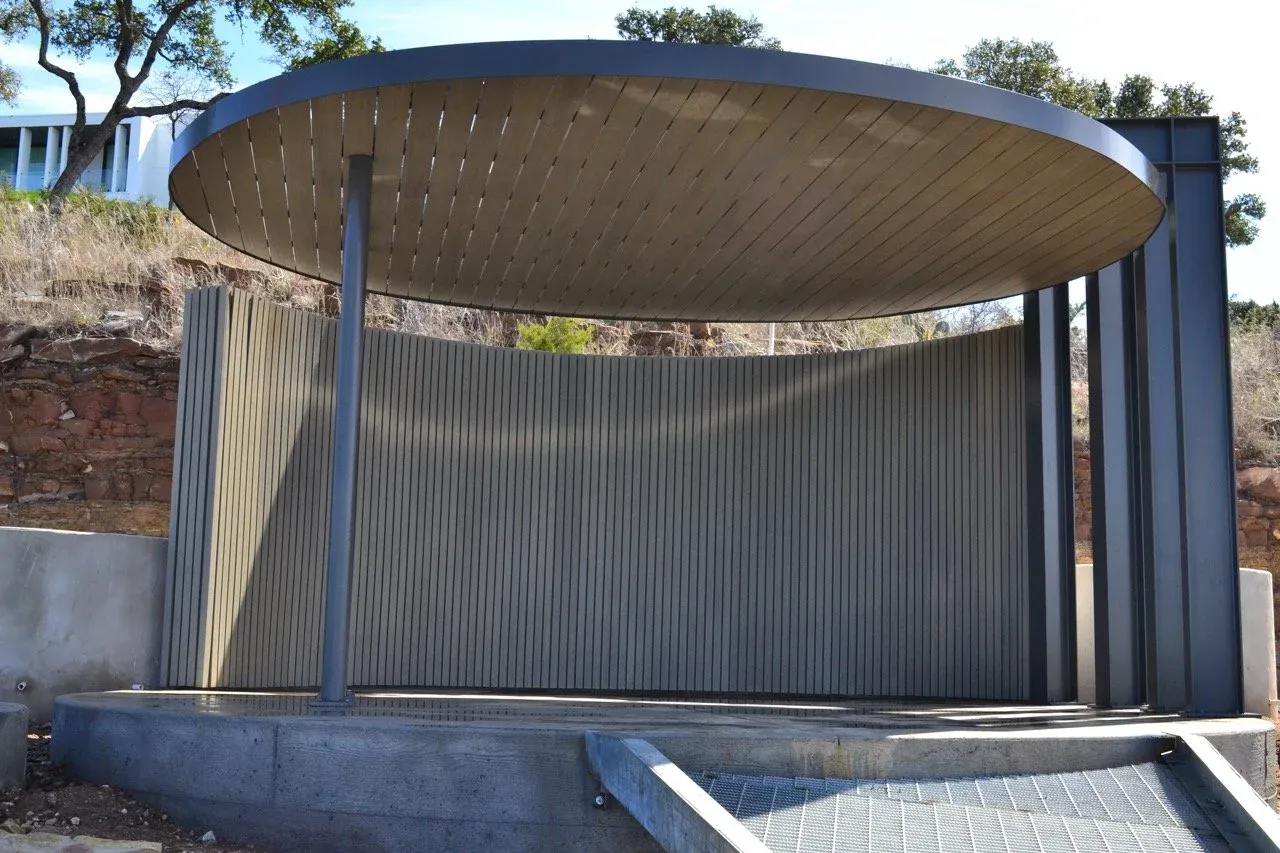 Front view of the round pavilion canopy and curved corrugated metal wall on a concrete pad