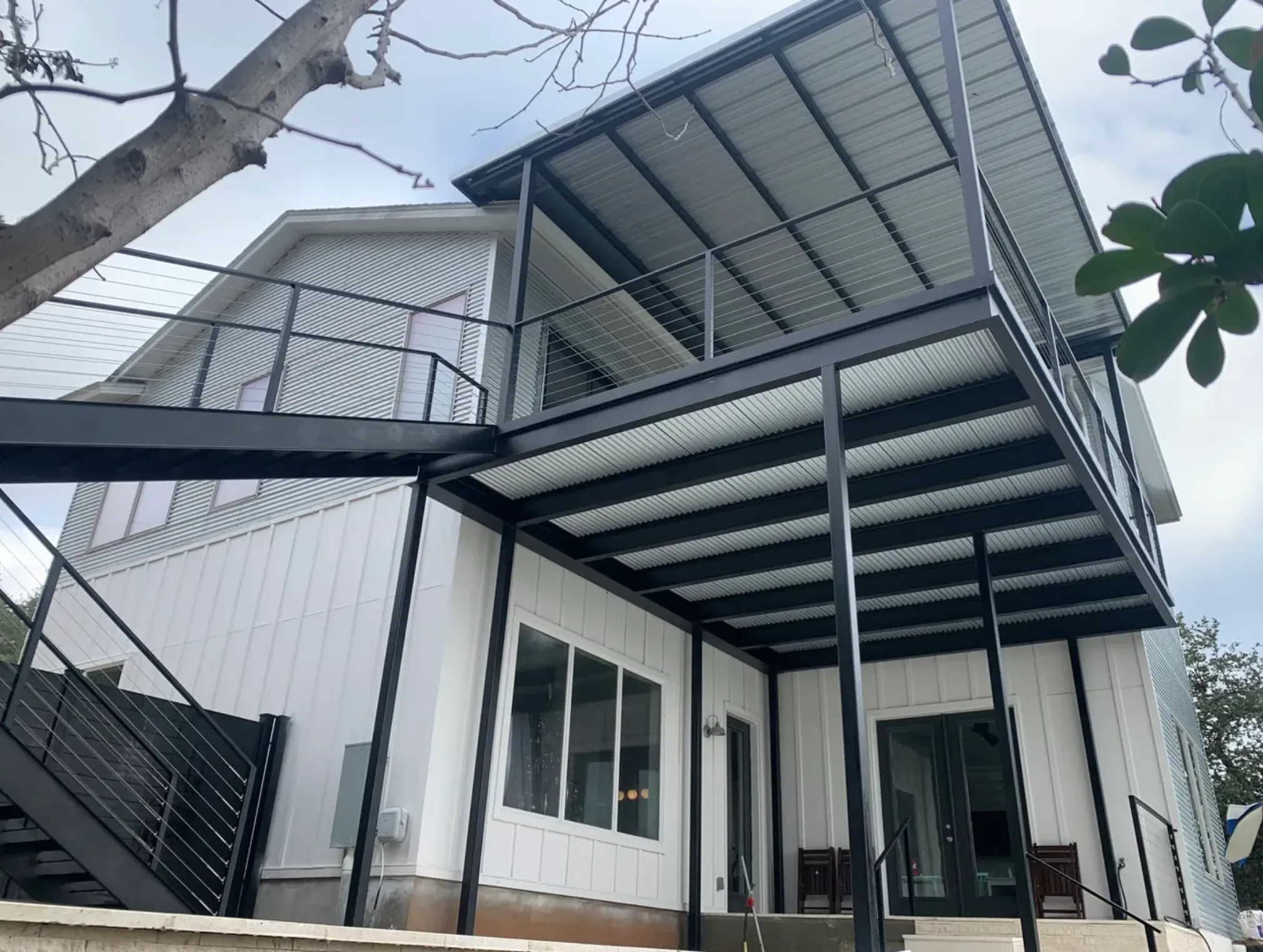Steel balcony, cable railing and exterior stairs on a white two-story house